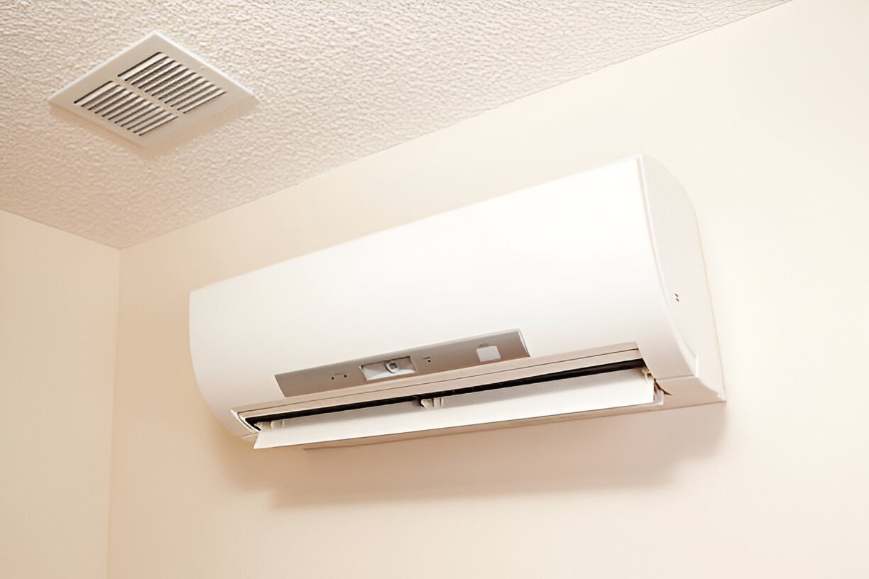 White wall-mounted air conditioning unit with vent above
