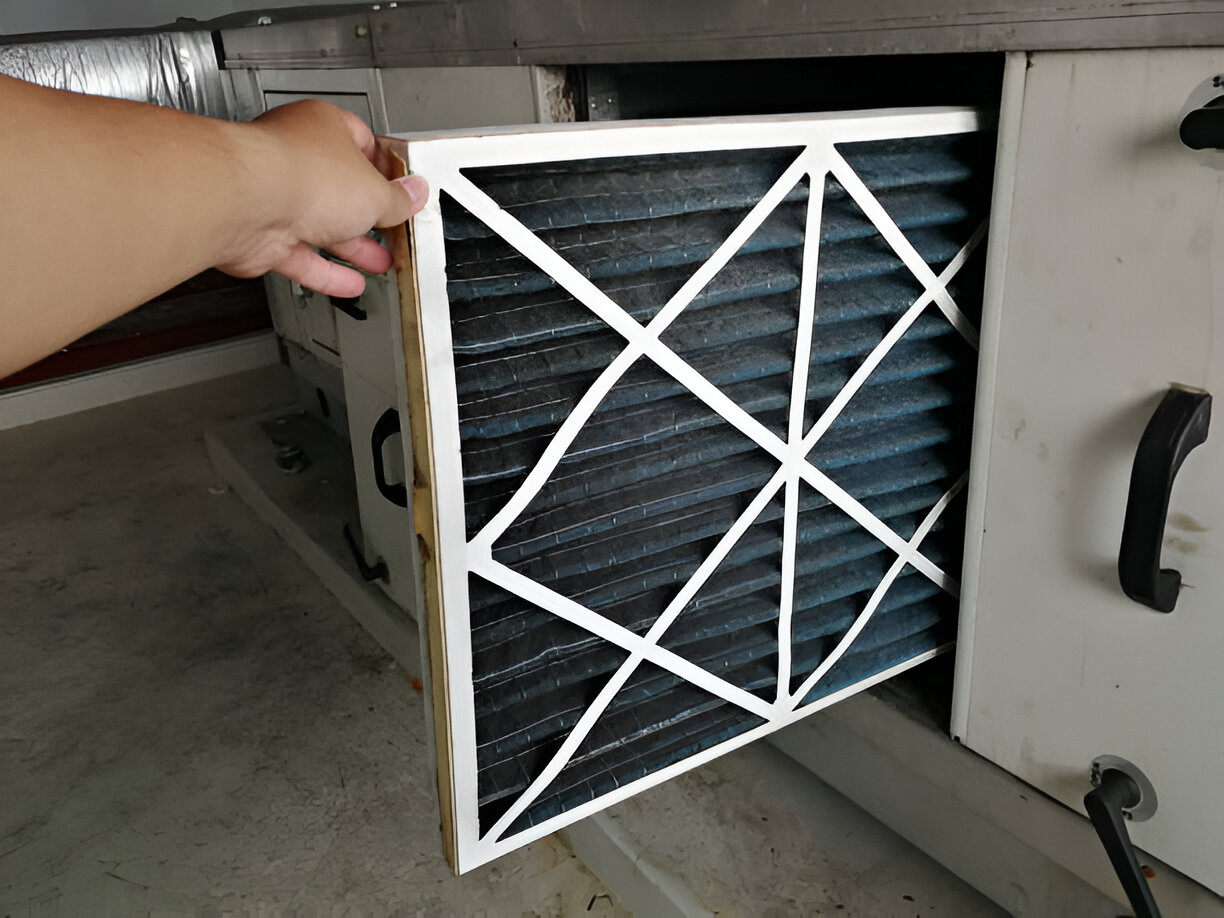 Dirty air filter being removed from HVAC system by hand