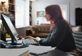 Young red hair woman sitting in the front of the computer