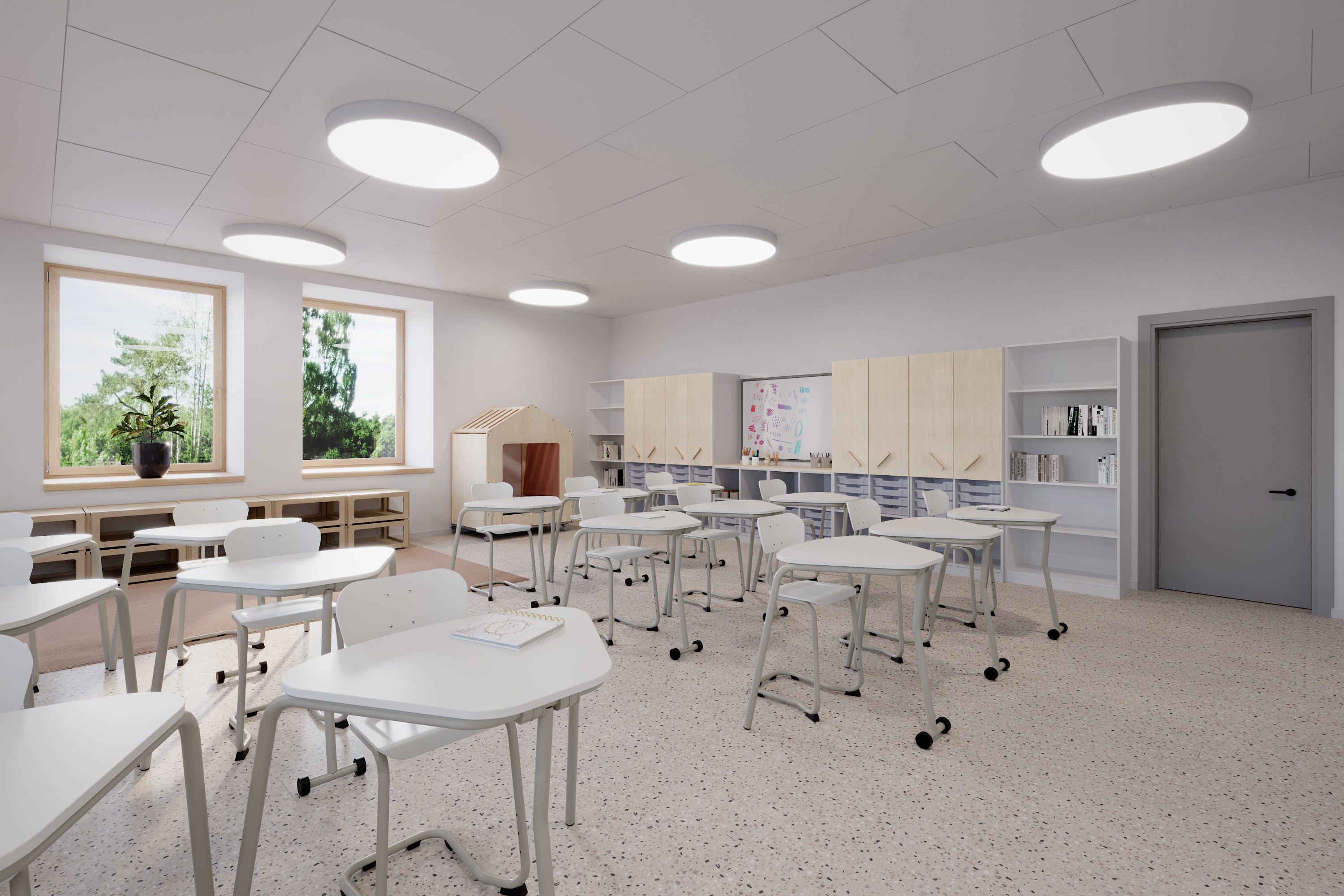 Ein Klassenzimmer mit Einzelsitzplätzen für den Frontalunterricht. Hochschränke an der Wand bieten viel Stauraum und ein Spielhäusschen neben den Fenster schafft einen Bereich für Rückzug. 