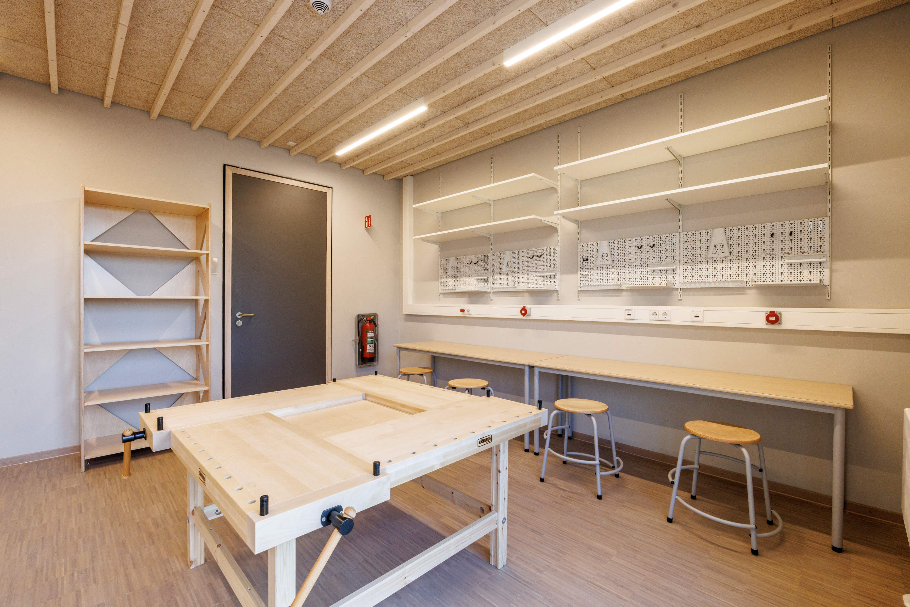 Werkraum für Kinder mit Werkbank und Werkzeugwand.