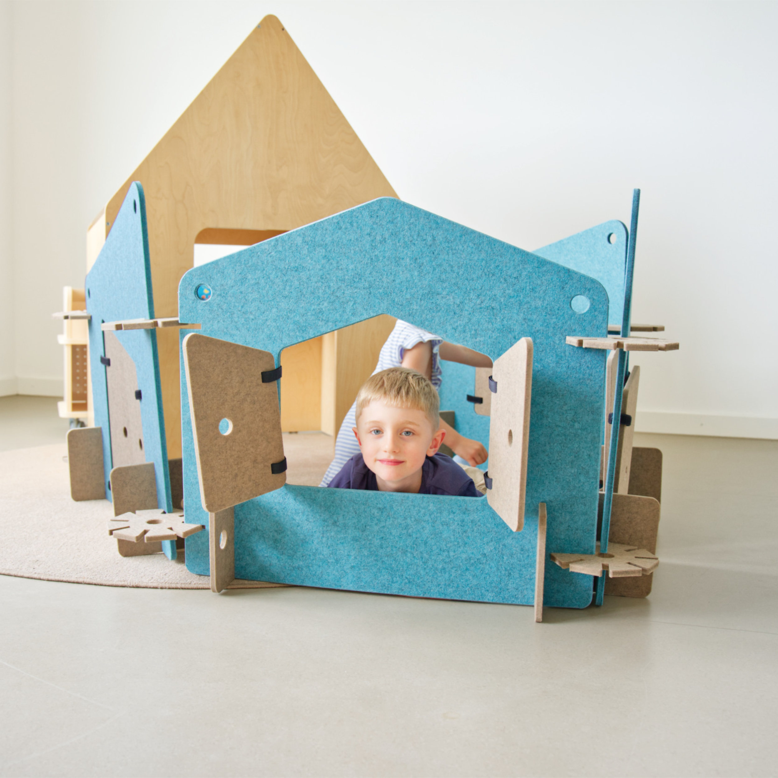 Junge schaut durch ein Fenster eines Spielzaunes aus PET-Filz.