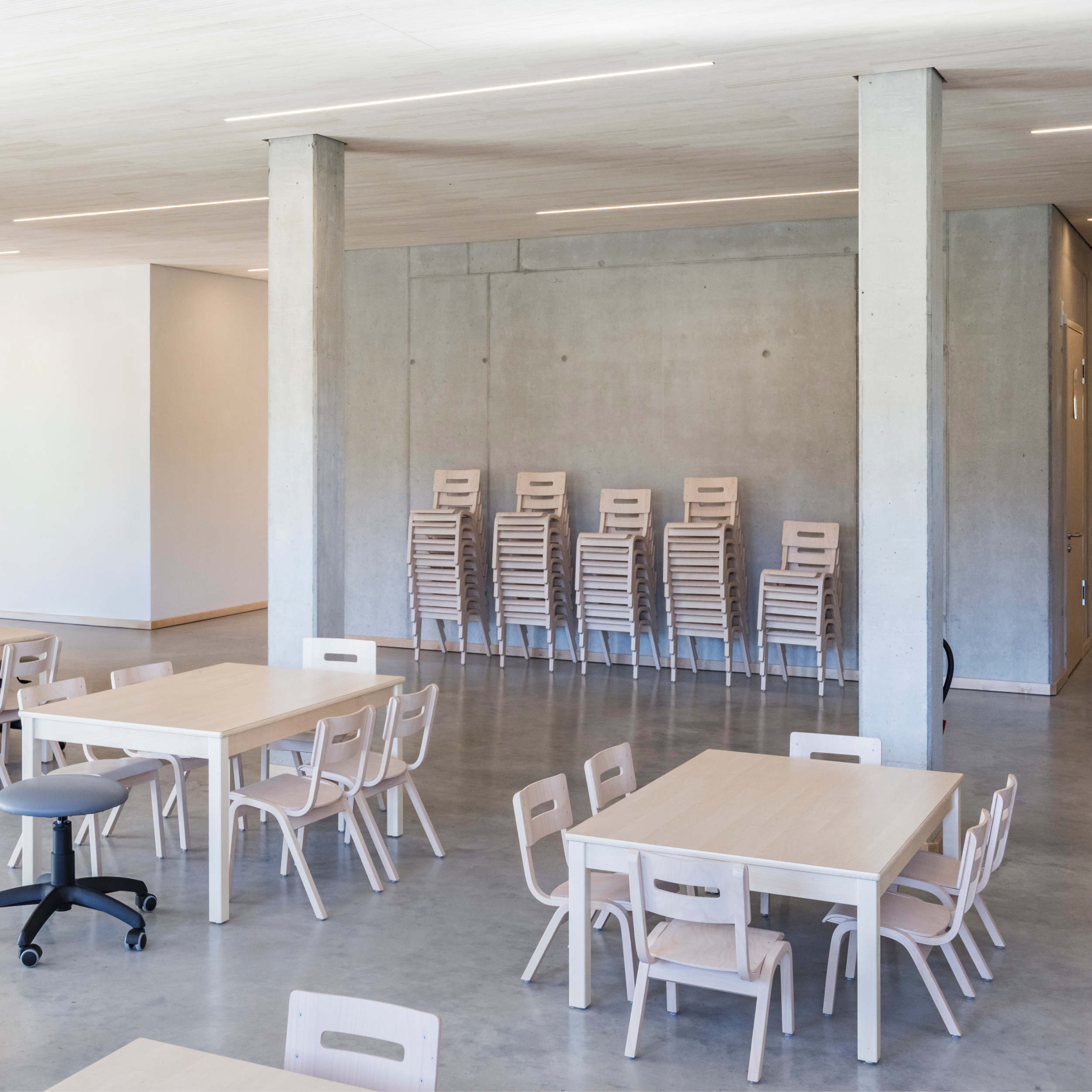 Ein Essensraum einer Kita mit hellen Tischen und Stühlen.