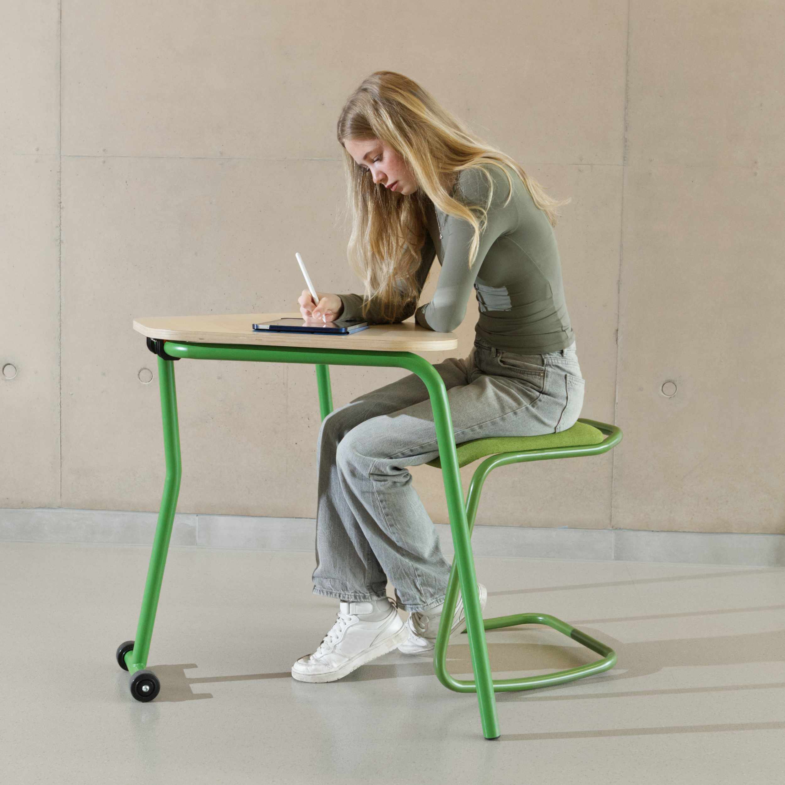 Ein Teenager-Mädchen klappt die Tischplatte eines Schulklapptisches nach oben