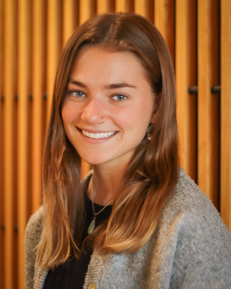 Smiling woman in gray sweater against wooden background