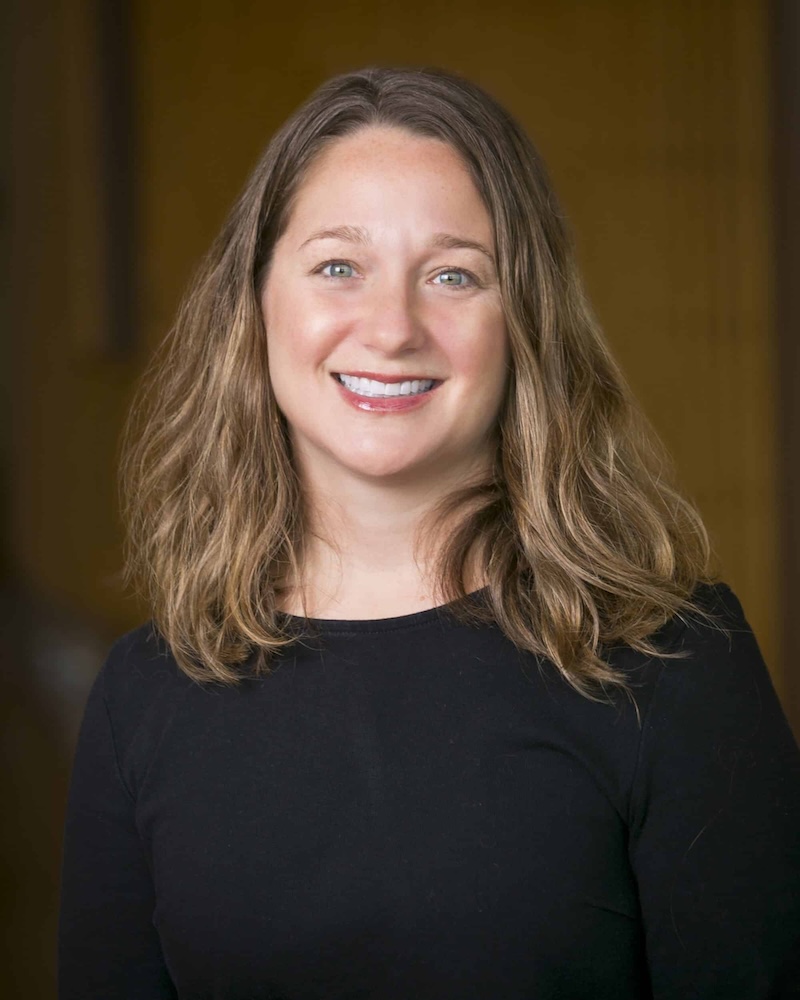 Portrait of a smiling woman with long brown hair wearing a black shirt