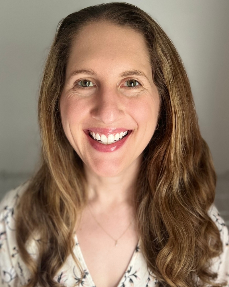 Portrait of a woman with long brown hair smiling brightly at camera
