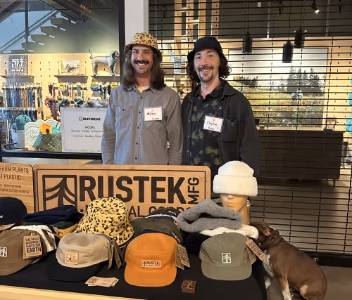 Two men standing next to a display of hats.