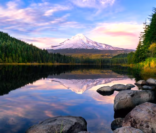 Serene lake reflecting a mountain and colorful sunset sky.