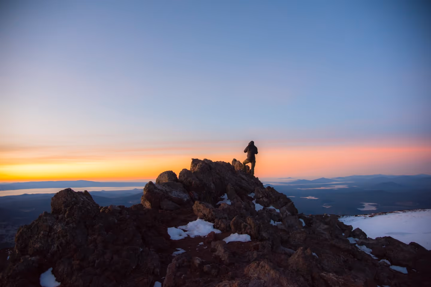 A person standing on top of a rocky mountain.