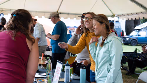A group of people standing under a tent.