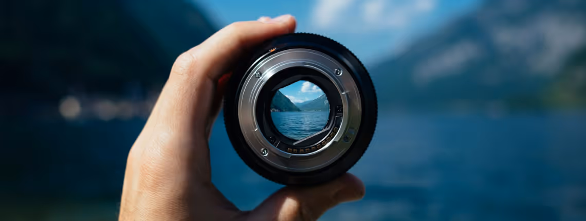 A close-up of a hand holding a compass with a blurred mountain landscape behind — symbolising agile navigation and strategic direction for startups.