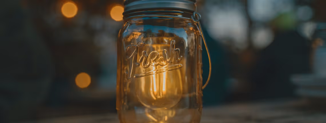 Lit candle in a glass jar with the word 'Dreams' — symbolising how authentic ideas glow but need structure to keep shining.