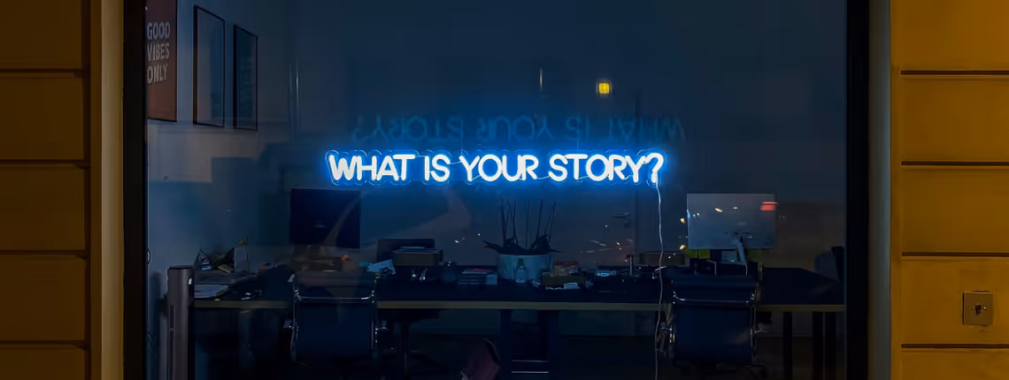Glass window with the neon words 'What is your story?' — symbolising the clarity and focus a founder’s story brings to a brand.