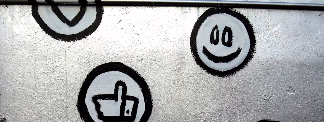Black and white graffiti-style wall with simple happy face icons and a thumbs-up symbol — representing loyal customers and early traction.