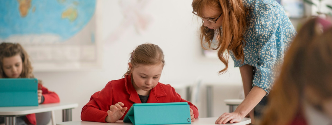 Teacher helping young students with digital tablets in a classroom — symbolising effective EdTech adoption and real classroom impact.