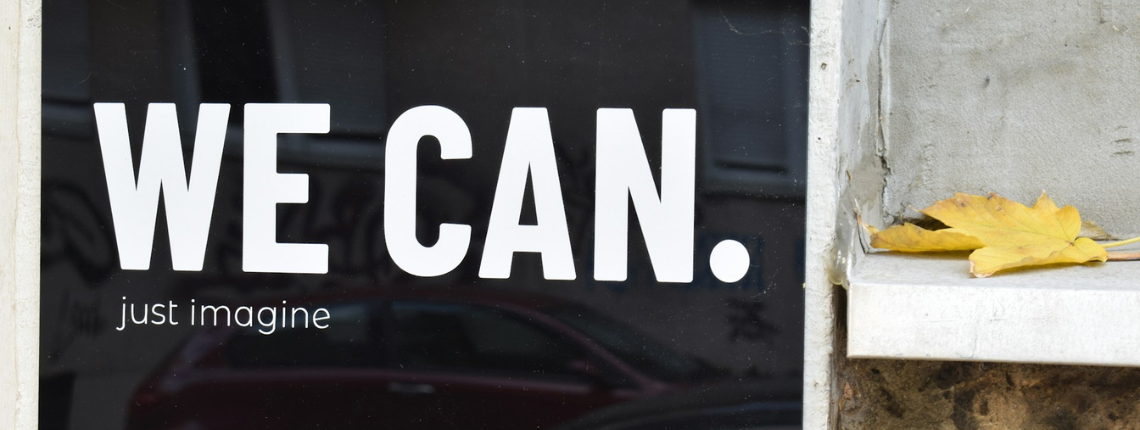 Black and white sign reading ‘WE CAN’ on a rustic wall — symbolising confident, operationalised intuition turned into repeatable growth.