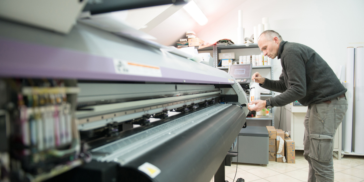 man cleaning a large format printer