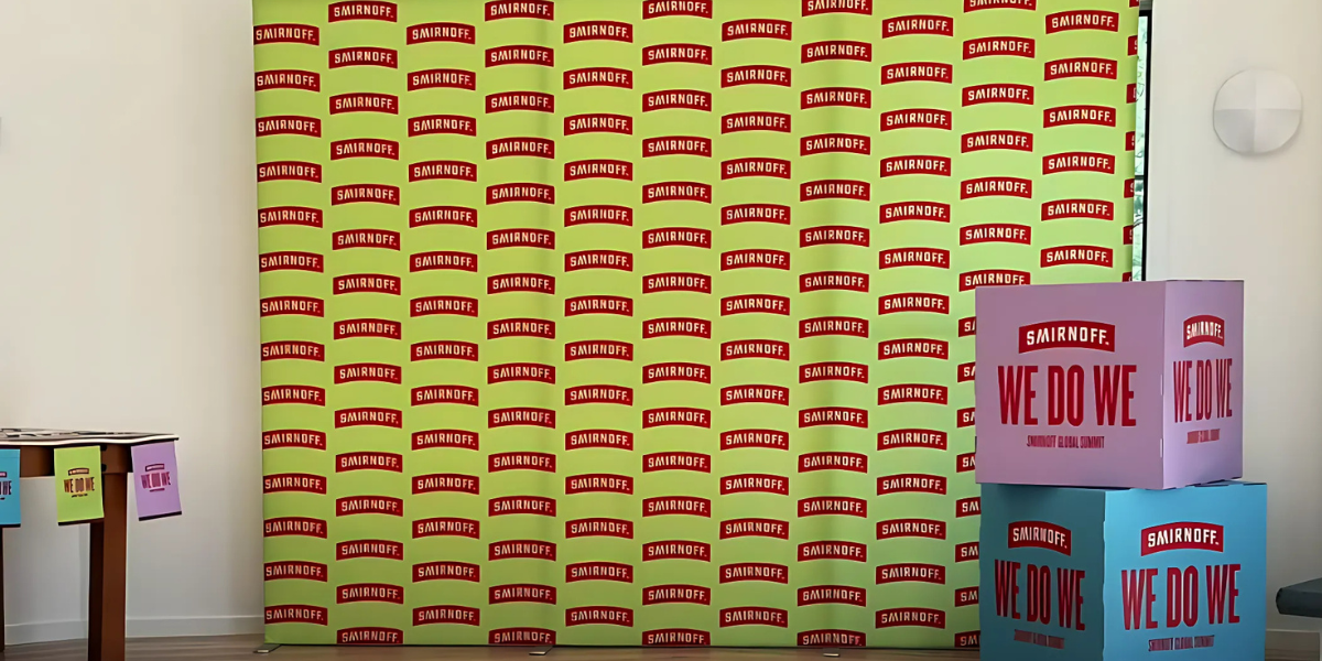 Large-format Smirnoff display with a branded backdrop and colorful We Do We boxes stacked beside it