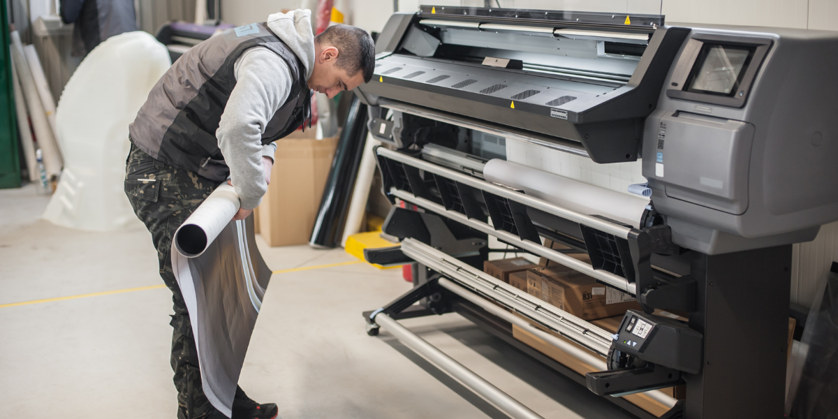 technician rolling up paper from a large printing machine