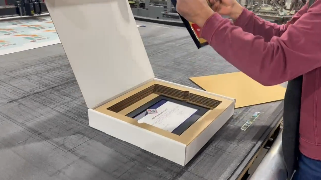 Person packaging a framed certificate inside a custom foam insert box
