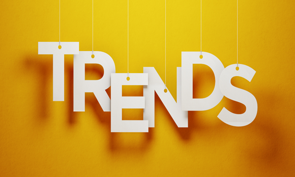 The word "TRENDS" hanging on strings against a bright yellow background