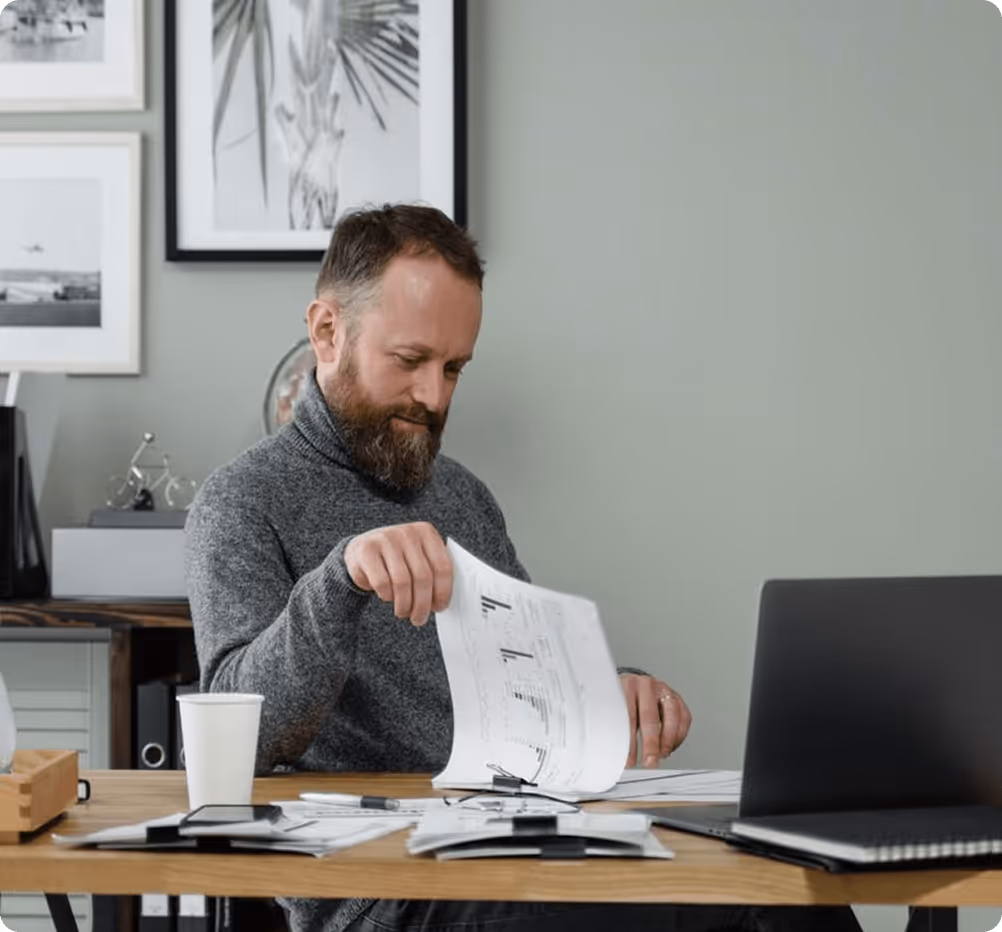 Professional reviewing documents at a desk, symbolizing FAQs about tech hiring solutions, engagement models, and developer availability at NIT Data.