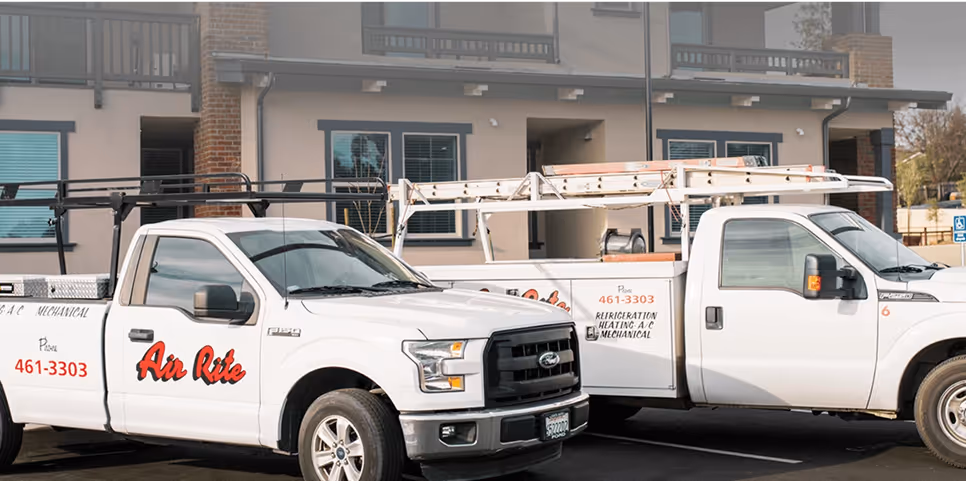 Two Air Rite service vehicles are parked next to each other.