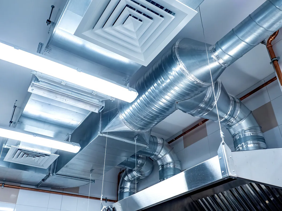 Metal ventilation ducts and lighting system in a commercial kitchen ceiling.