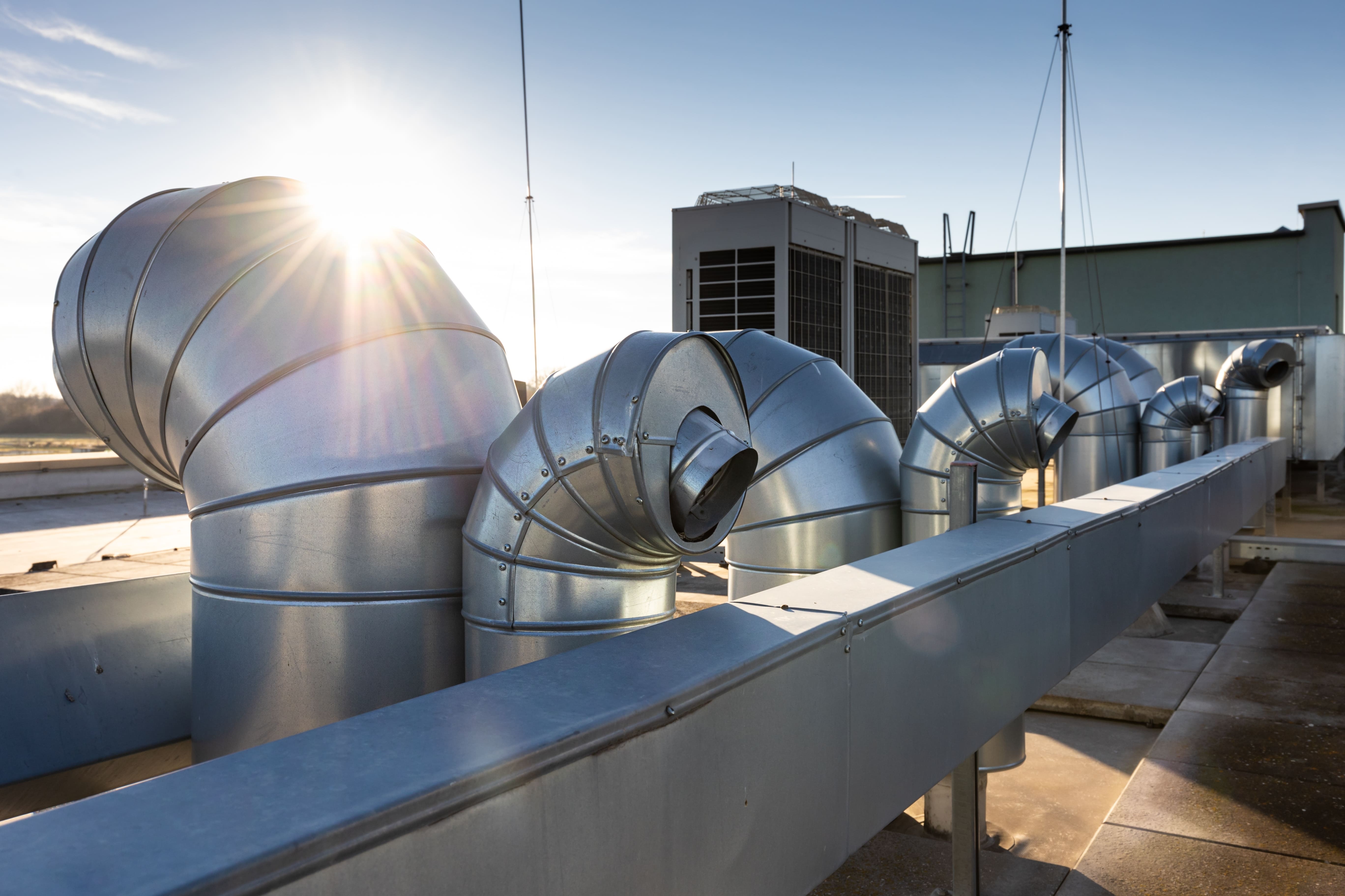 A commercial building rooftop with HVAC equipment and ducting.