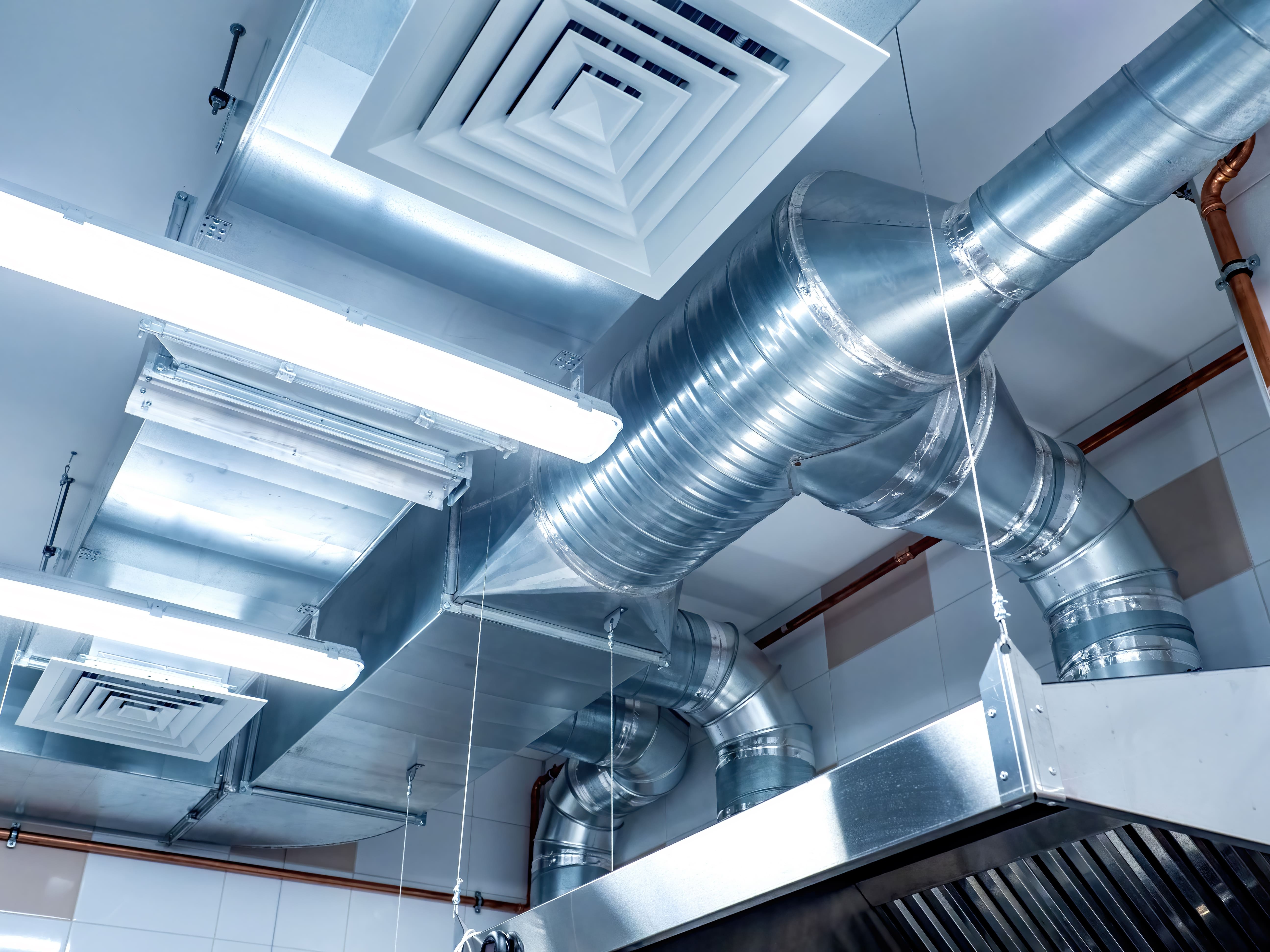 Ventilation ducts and lights in a modern commercial kitchen for efficient air circulation.
