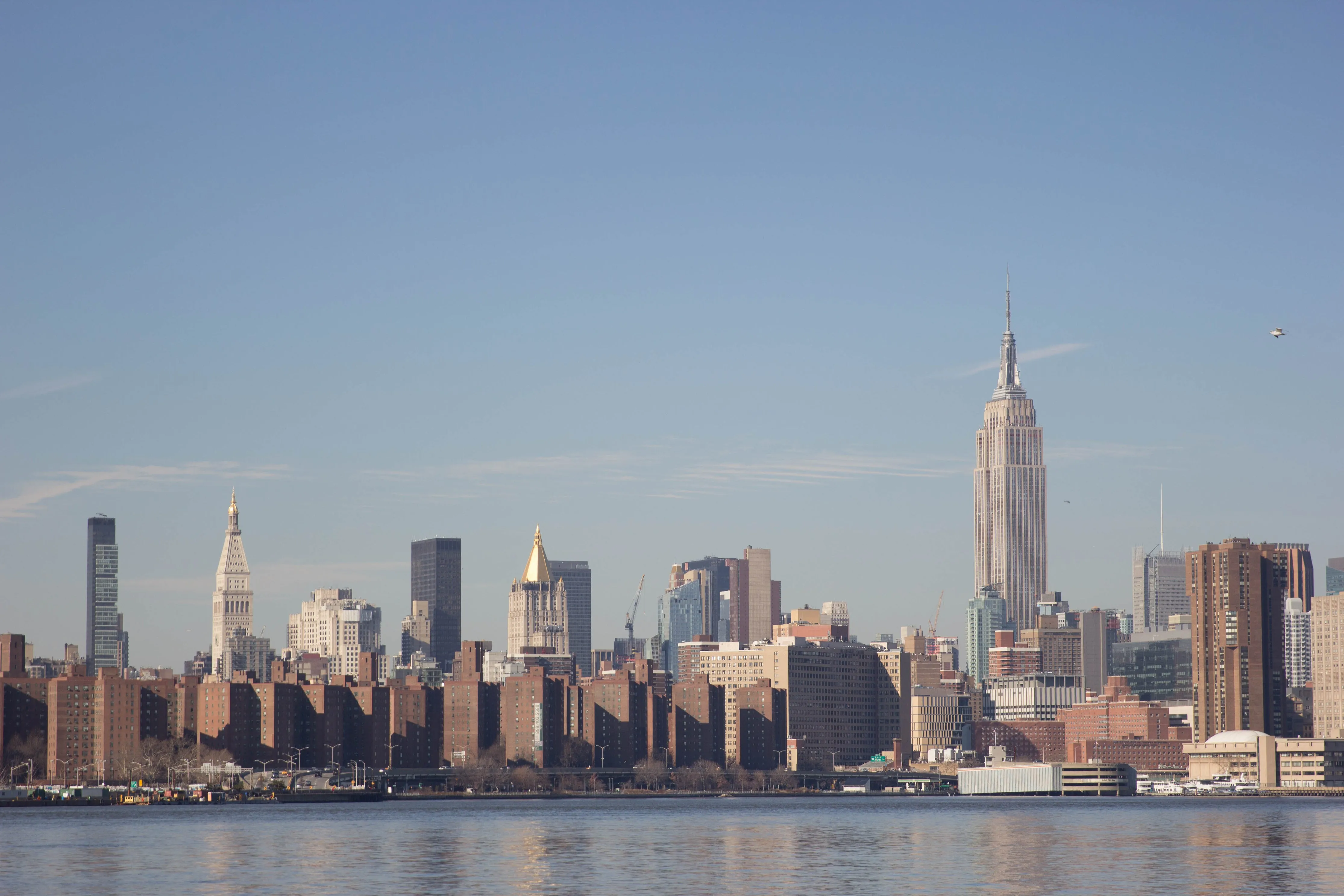 Midtown Manhattan skyline with the Empire State Building reflected in the East River.