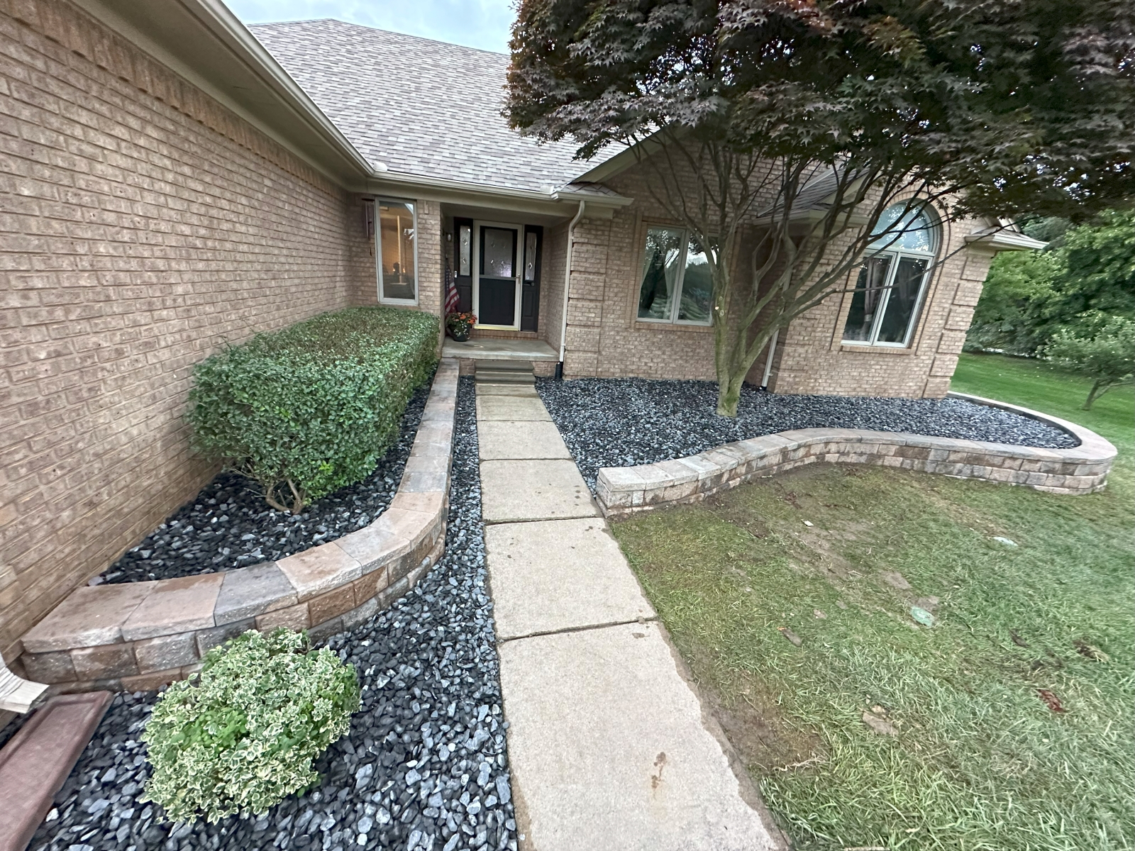 Front yard renovation featuring black slate rock, natural edging, and retaining wall installed by JB Landscaping in Macomb, MI