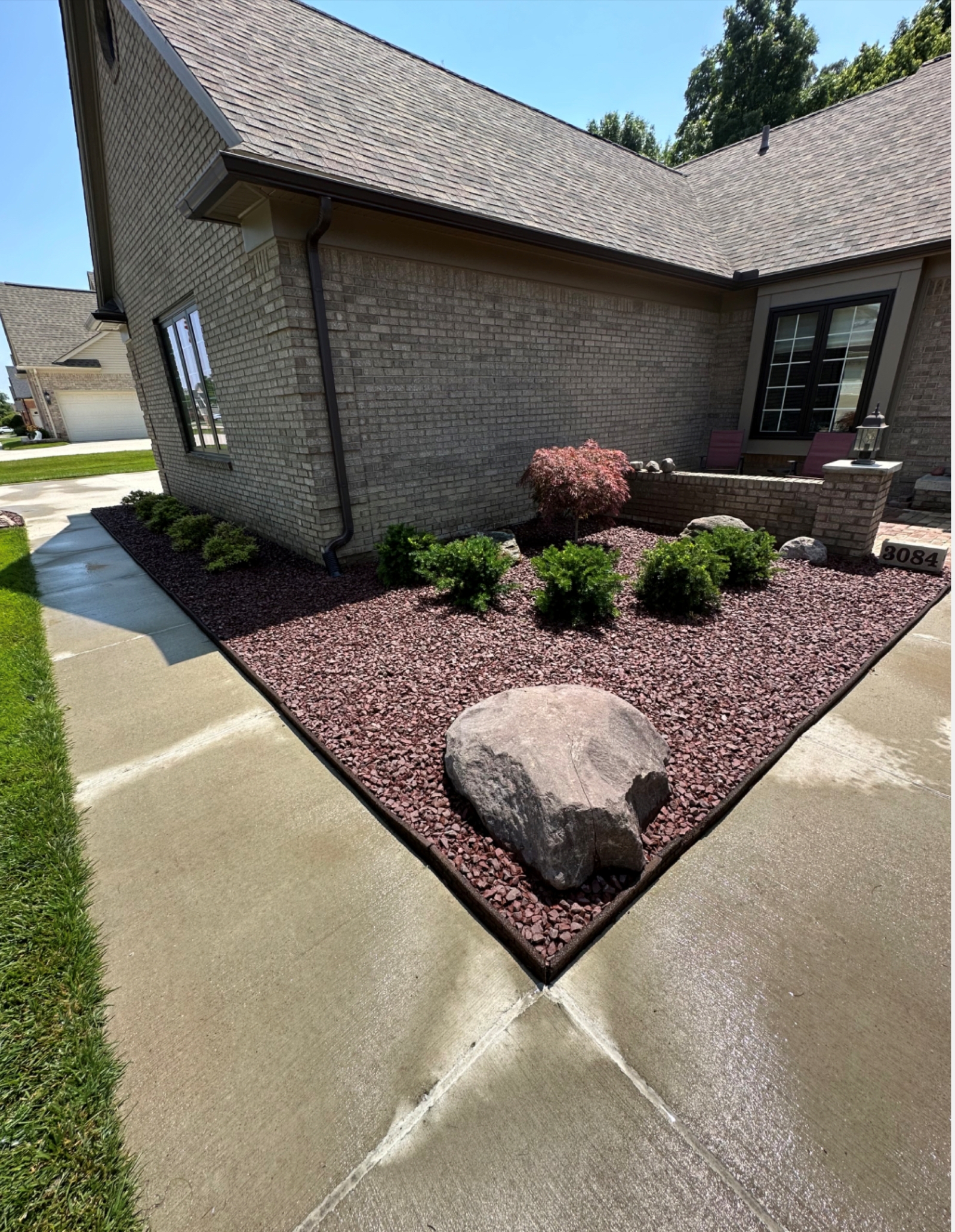 Decorative red rock bed installation with polished edging by JB Landscaping in Macomb, MI