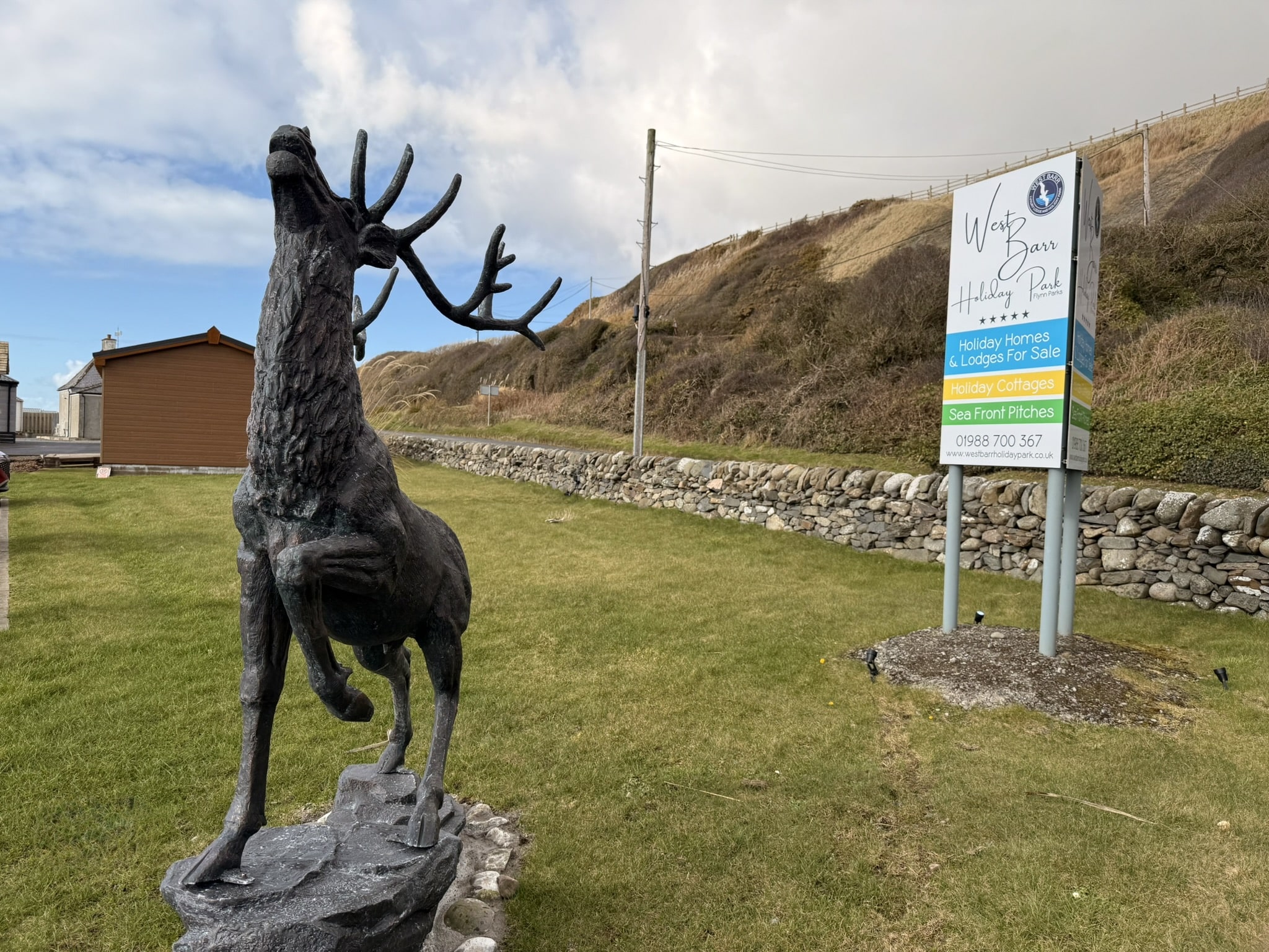 Black stag statue at West Barr Holiday Park with stone wall and sign