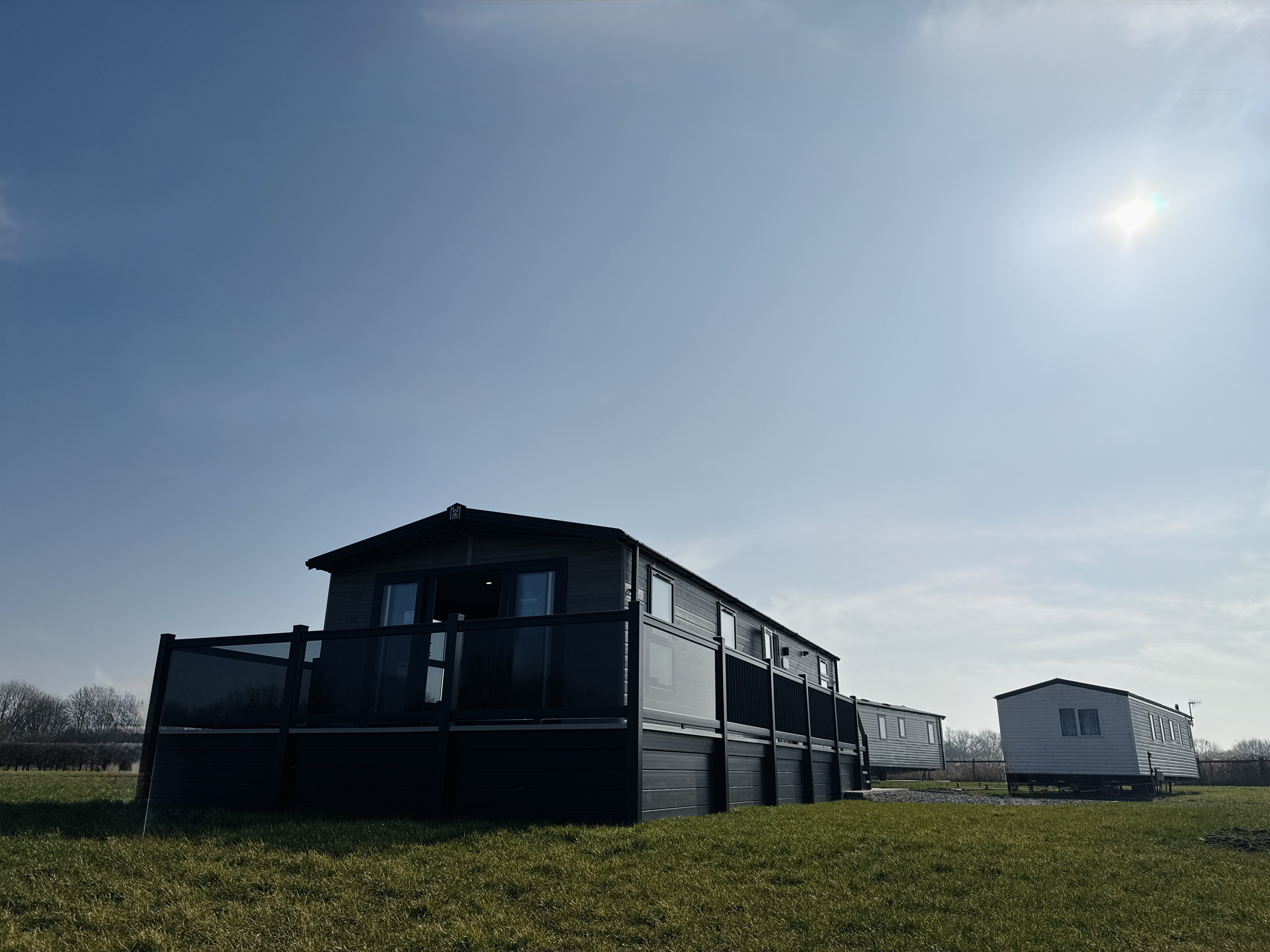 Black and white mobile homes on grassy field under bright sky