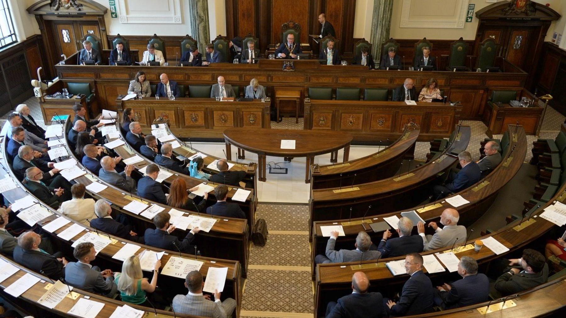 Government chamber with officials seated in curved wooden benches