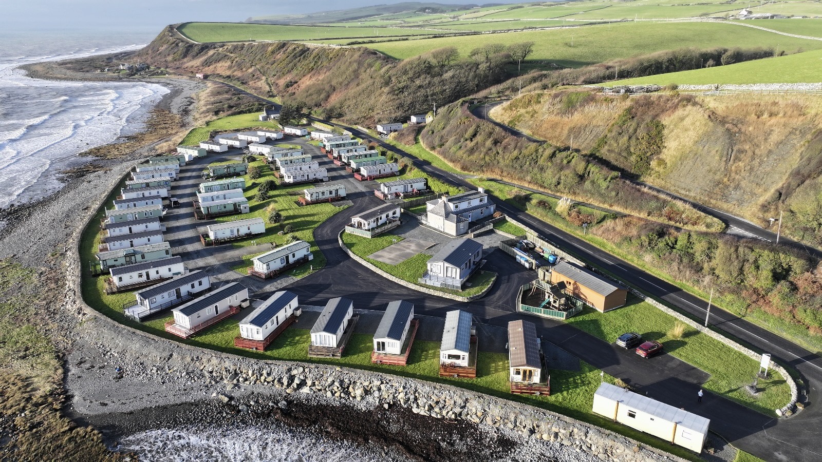 Coastal trailer park with white mobile homes nestled on rocky shoreline