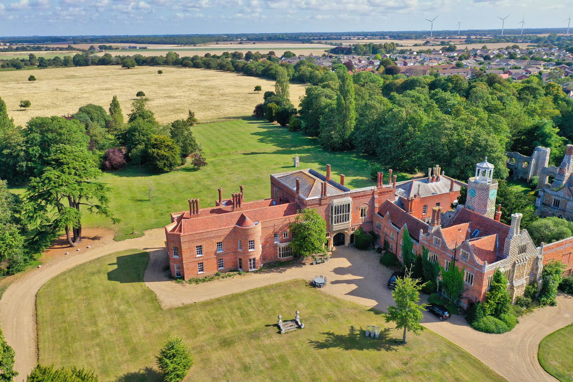 Aerial view of historic red brick manor house surrounded by lush green grounds