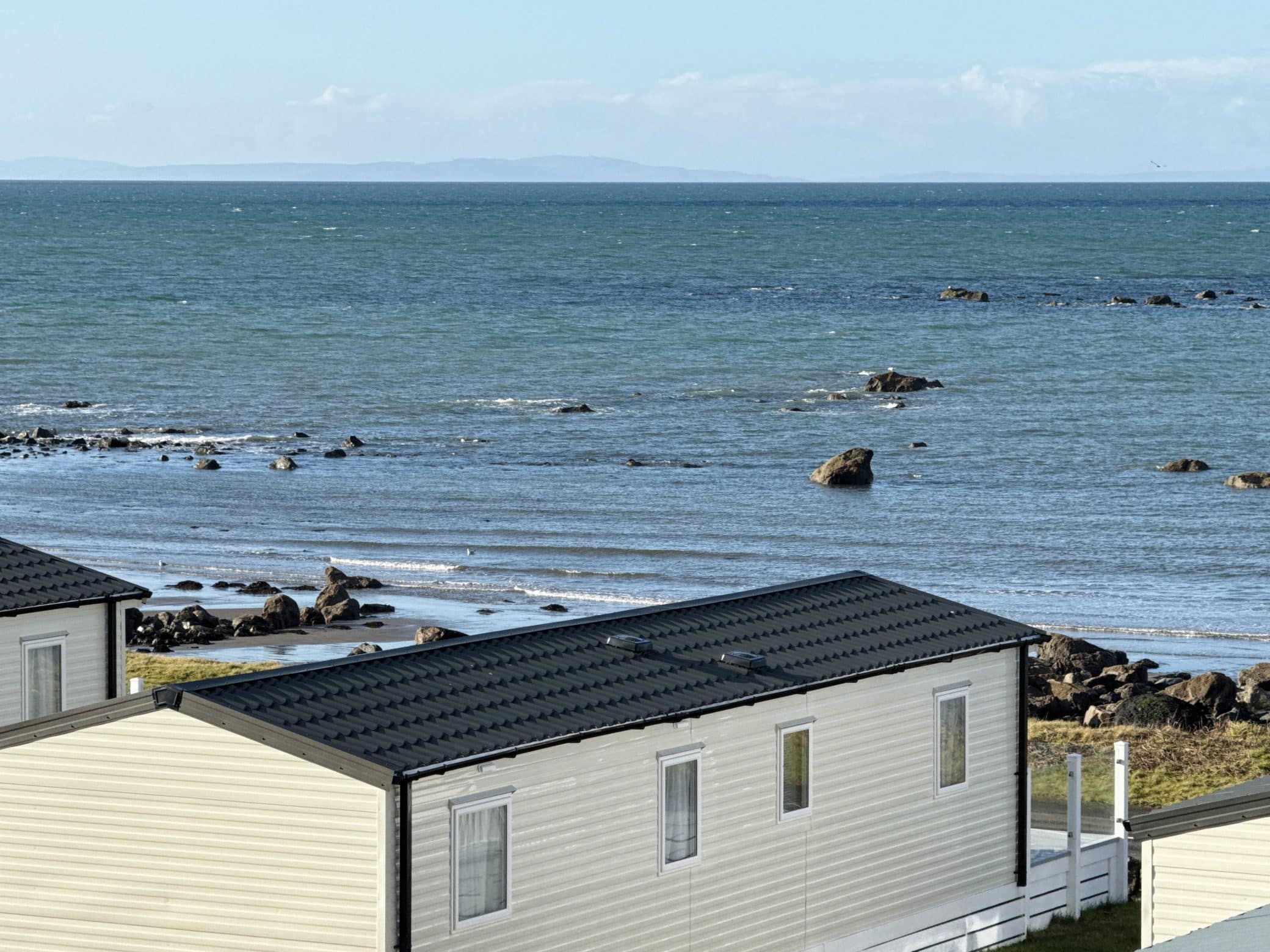 Coastal mobile homes with rocky shoreline and calm blue sea view