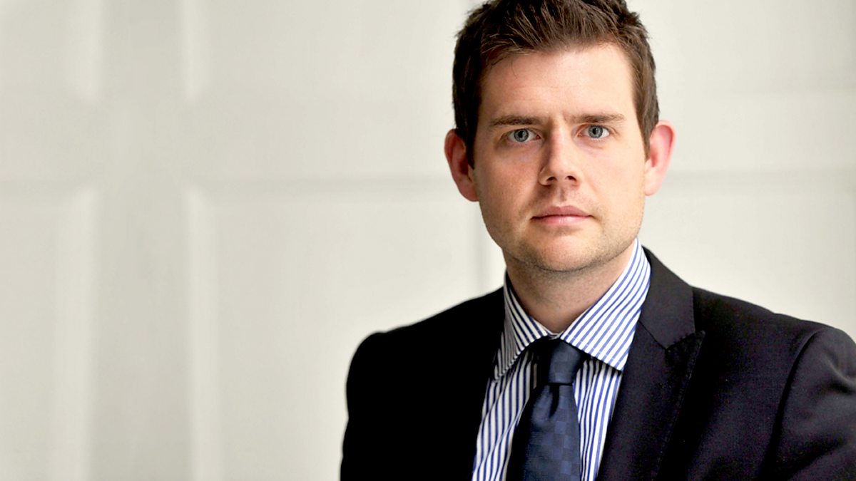 Professional man in black suit and striped shirt looking directly at camera