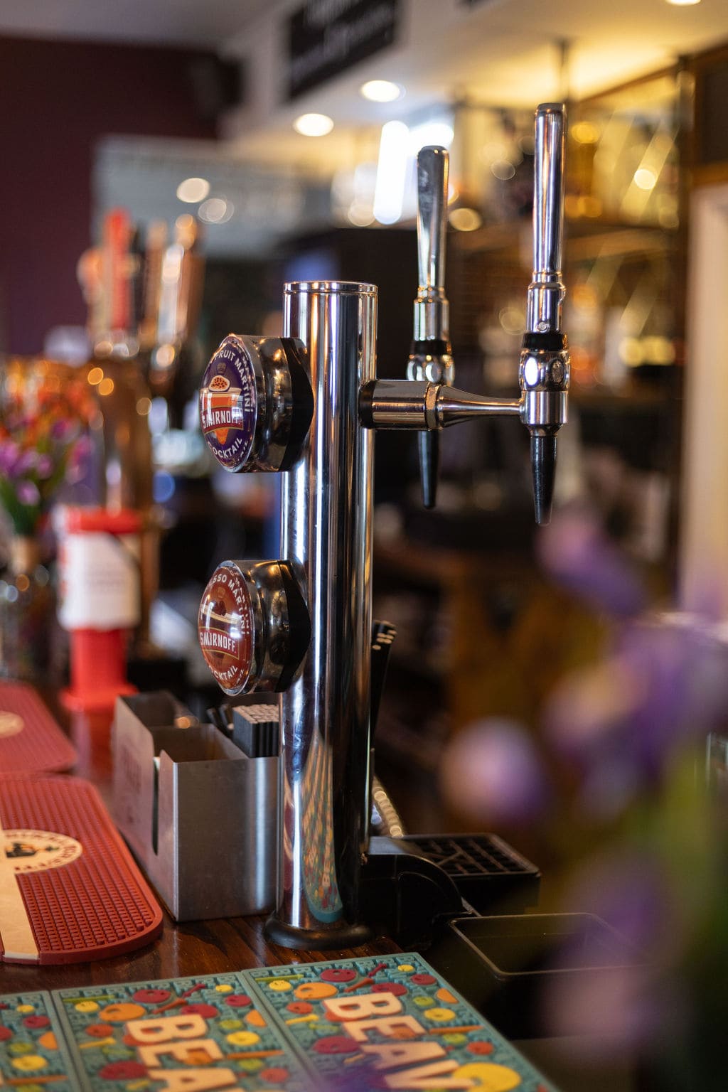 Beer taps and Smirnoff signs on bar counter with colorful coaster