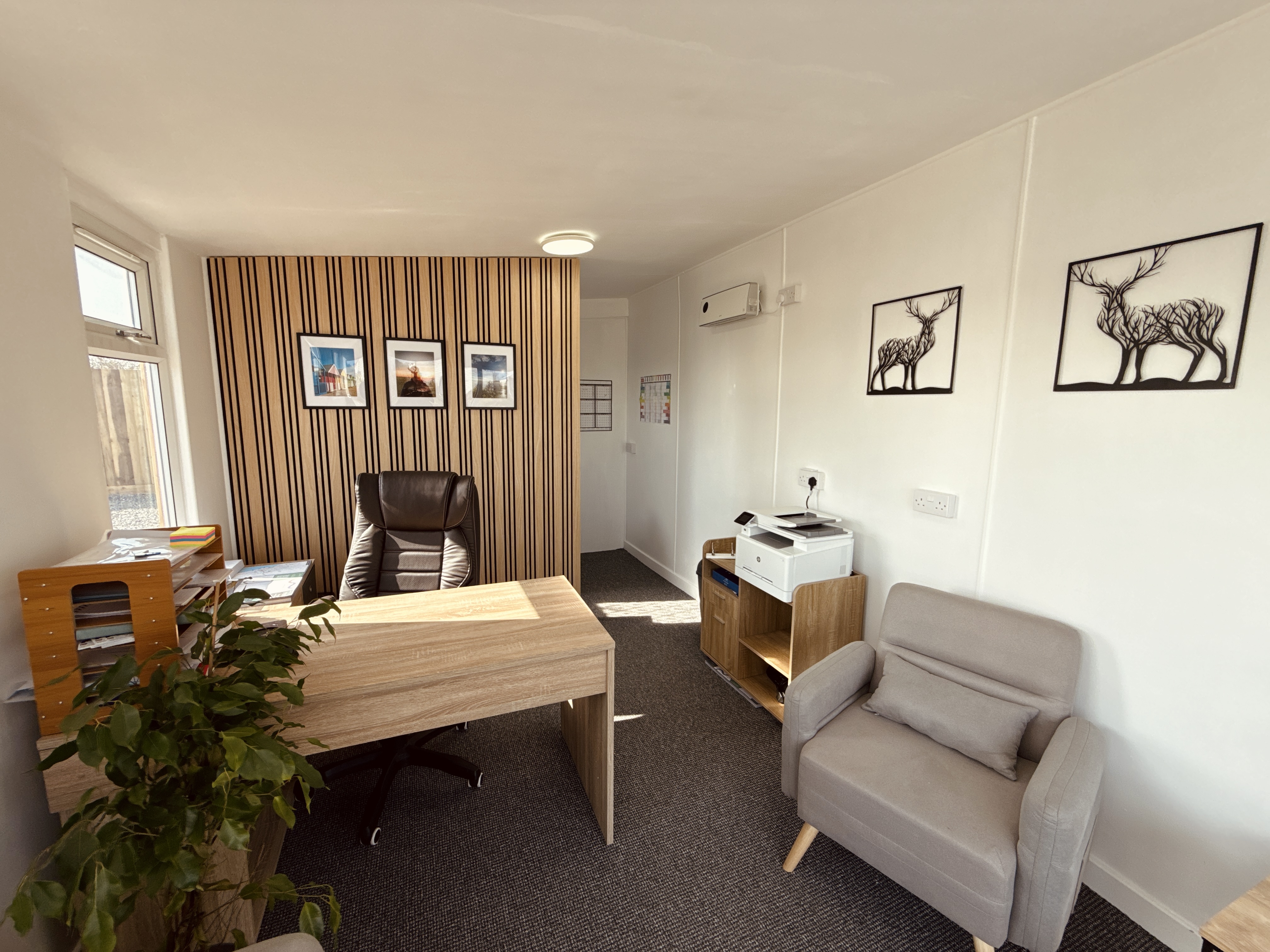 Modern home office with wooden desk, deer artwork, and comfortable chairs