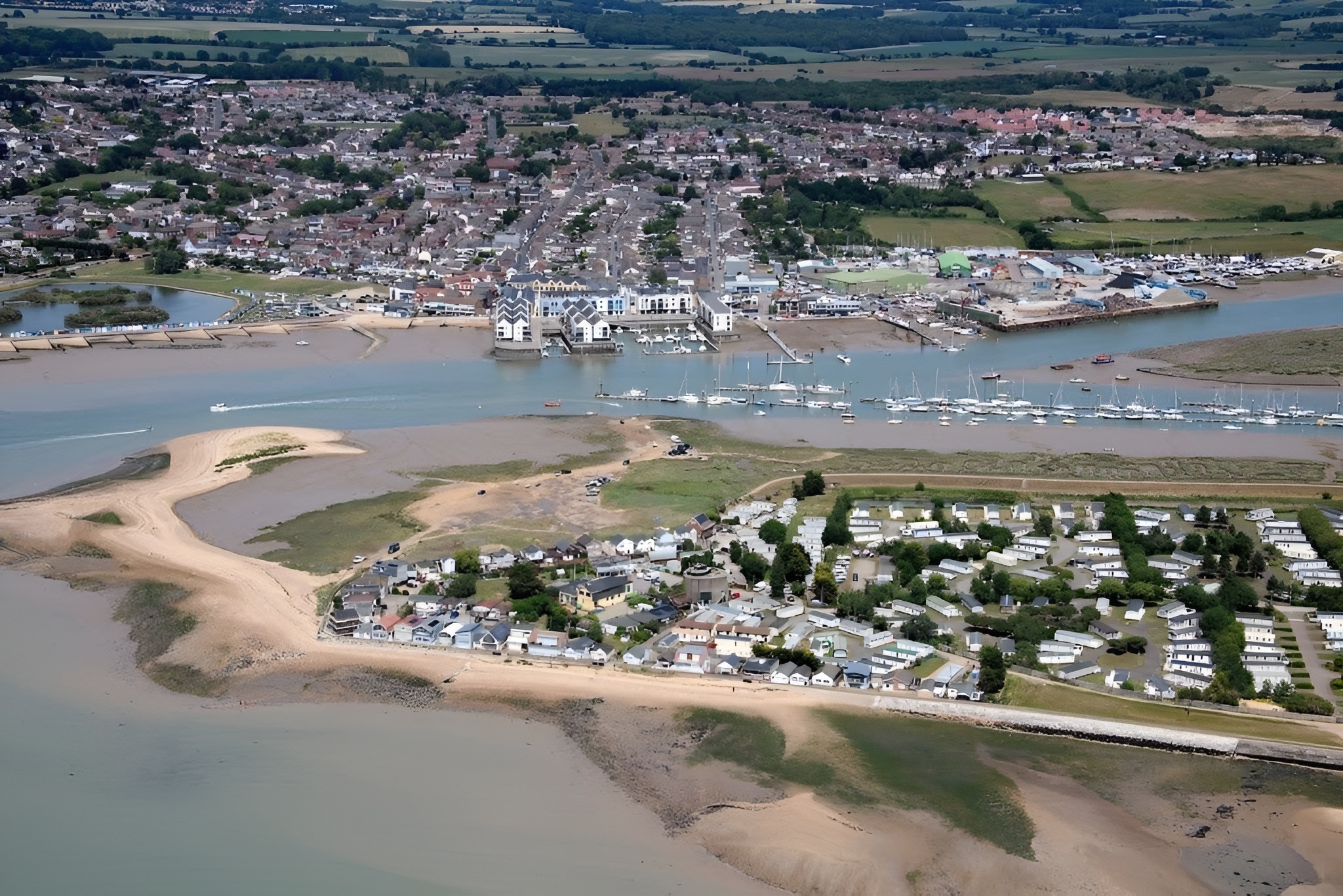 Aerial view of coastal town with marina, sandy beaches, and residential areas