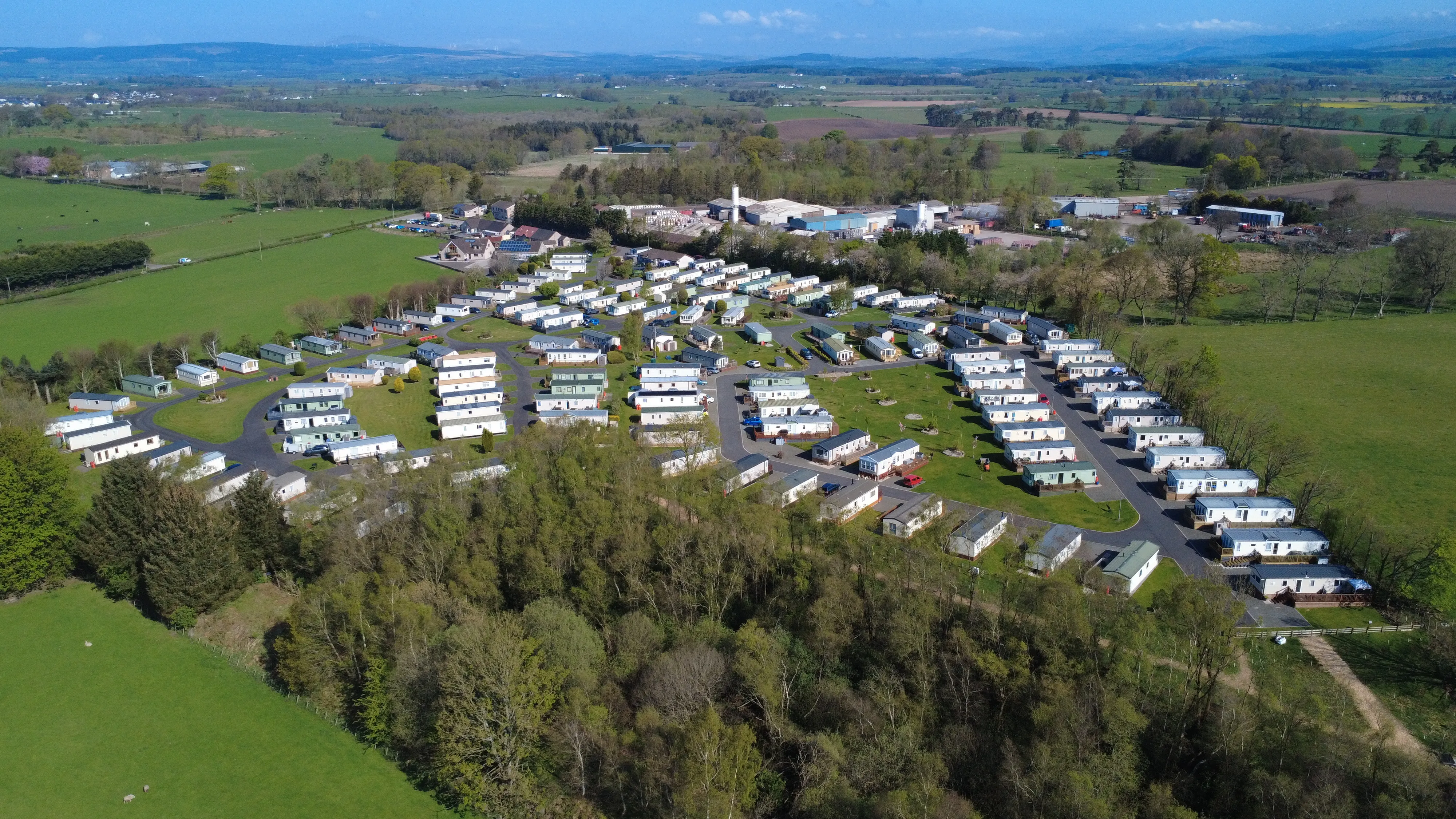 Aerial view of mobile home park surrounded by green fields and mountains