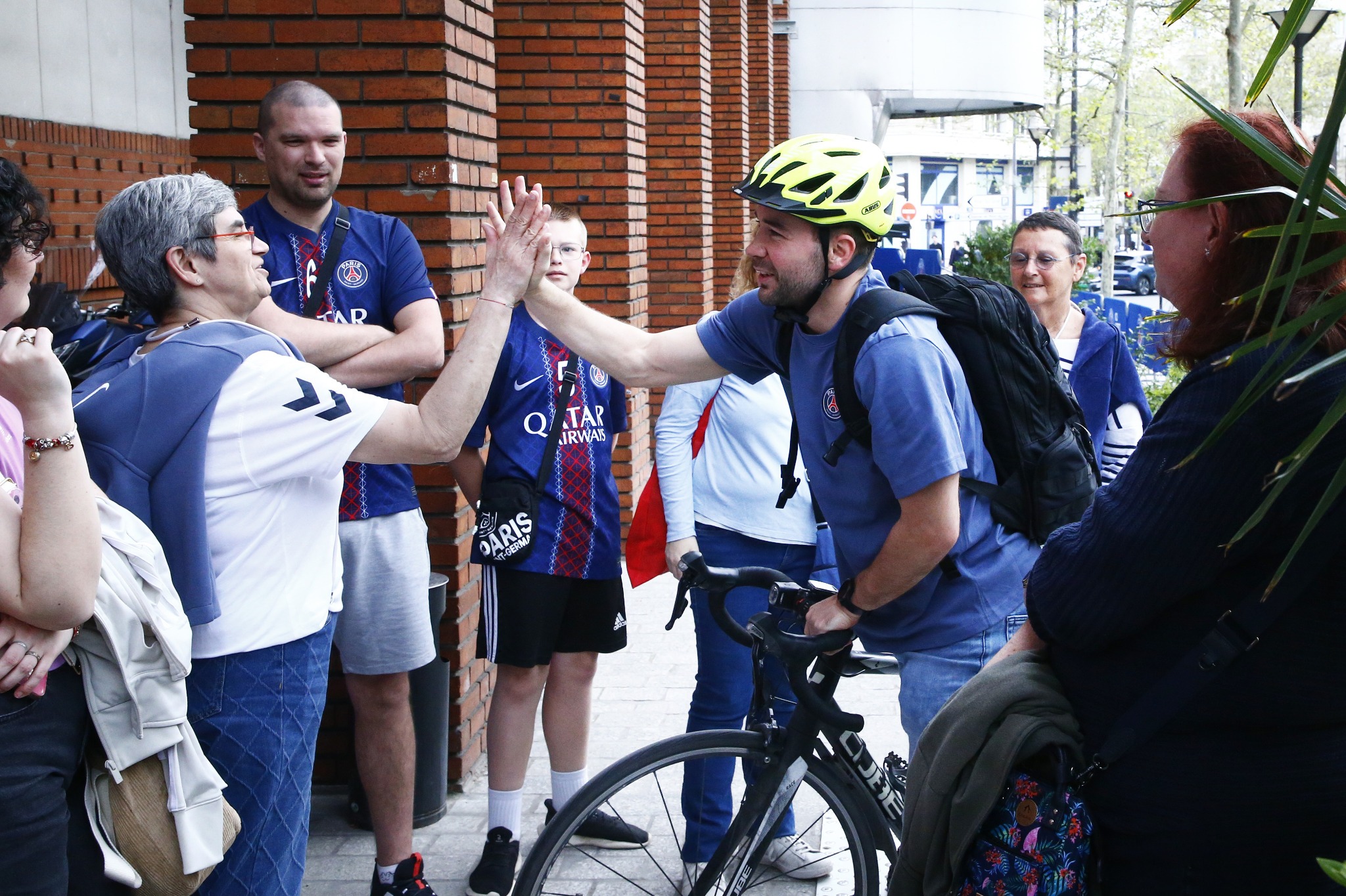 Luc Steins arrivant à vélo au Stade Pierre de Coubertin, échangeant avec des supporters.