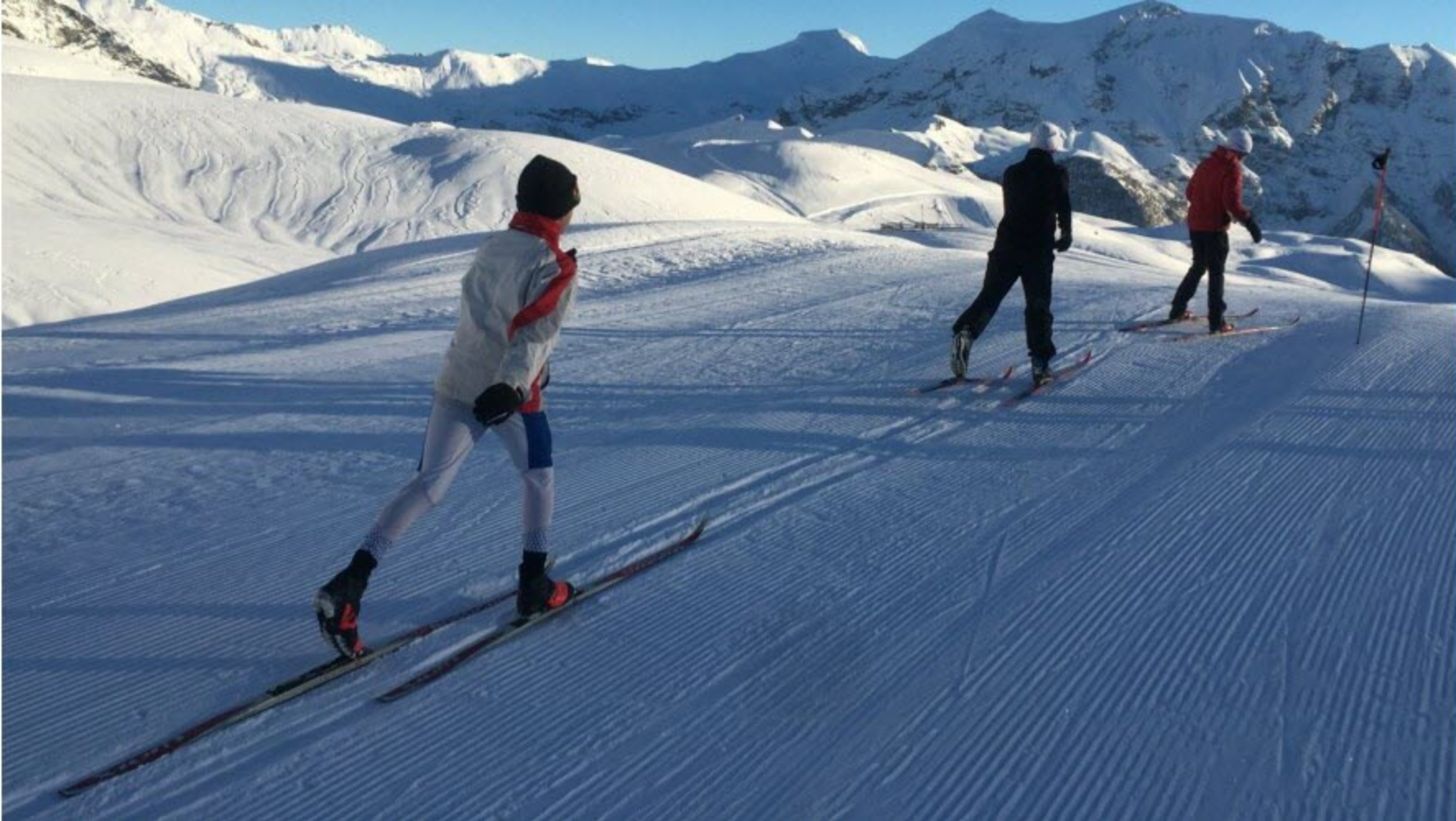 Trois jeunes skieurs de fond, adhérents du club, progressent sur une piste enneigée, au cœur d’un paysage de montagne.