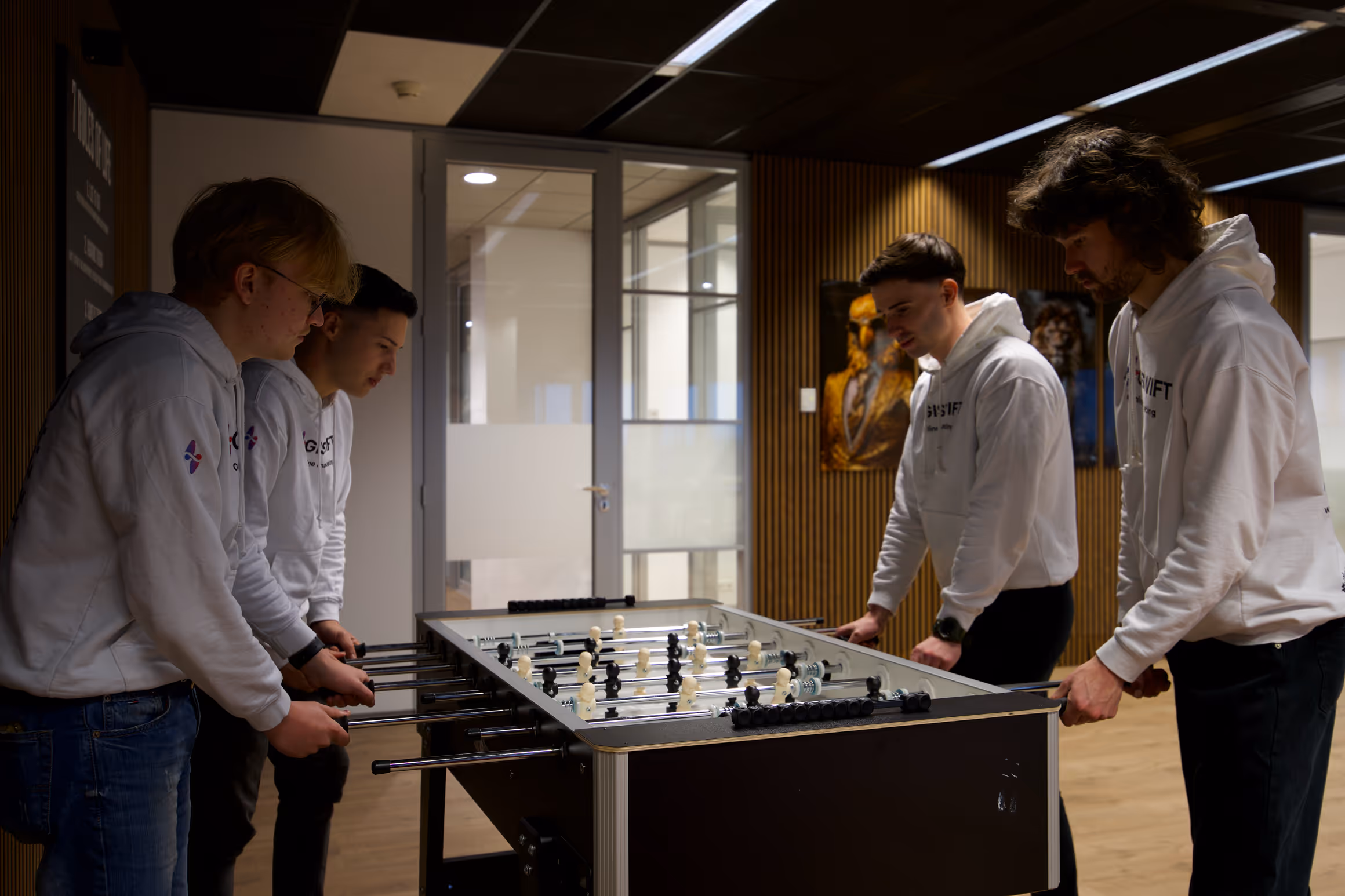 Het team van DigiSwift speelt tafelvoetbal in moderne kantoorruimte als onderdeel van teambuilding en samenwerking