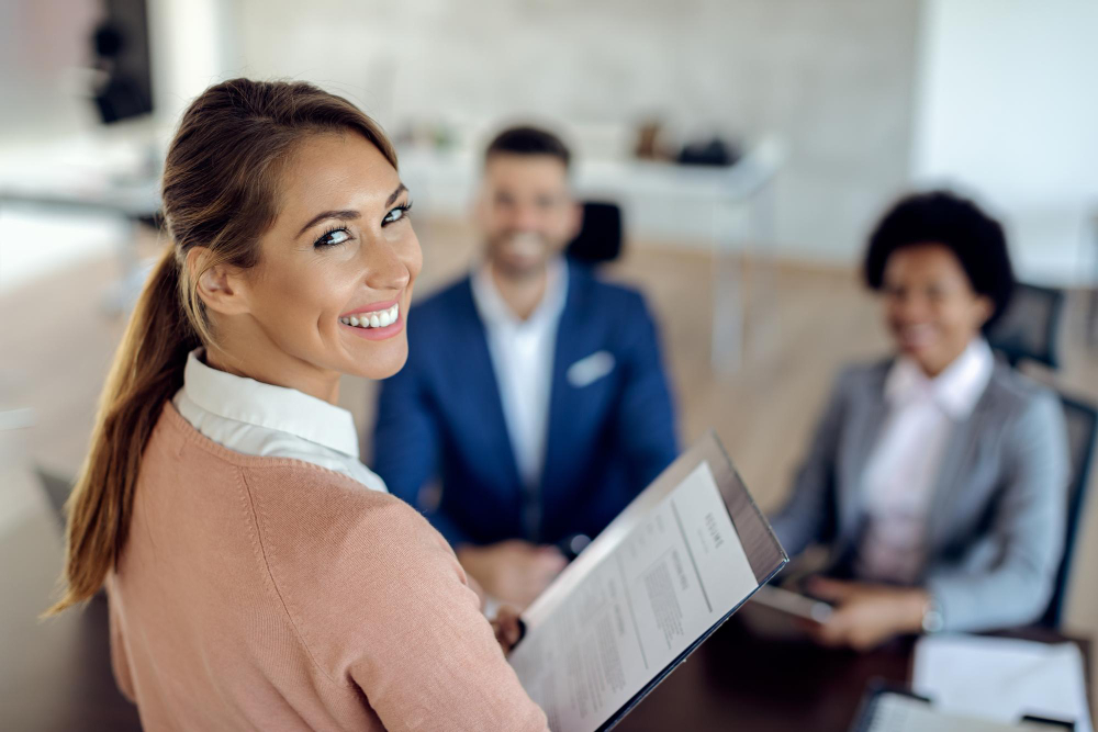 Vrouwelijke sollicitant glimlacht tijdens een sollicitatiegesprek met twee recruiters aan tafel.