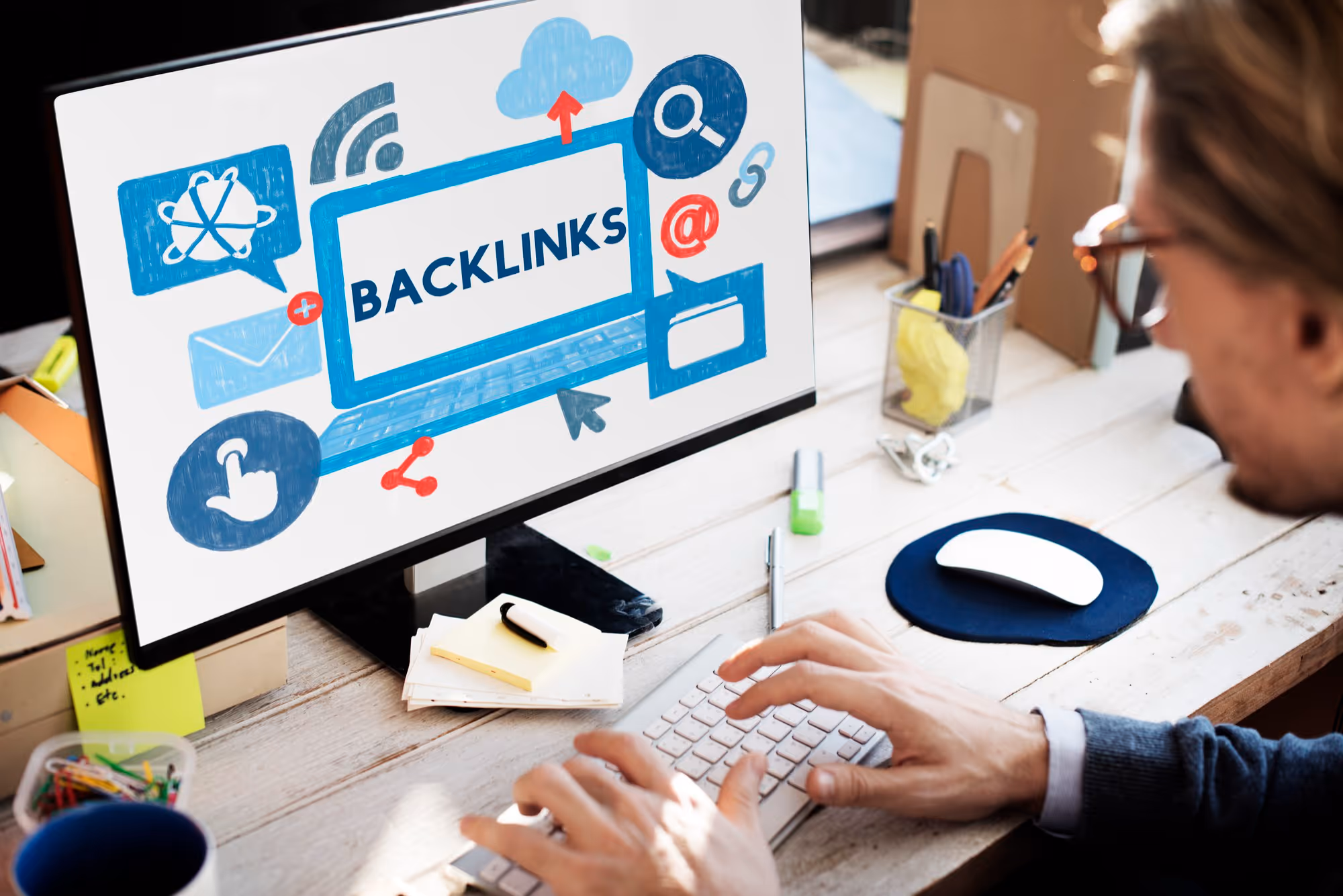 Man werkt aan computer met het woord “Backlinks” op het scherm, illustratie van linkbuilding en SEO-analyse.